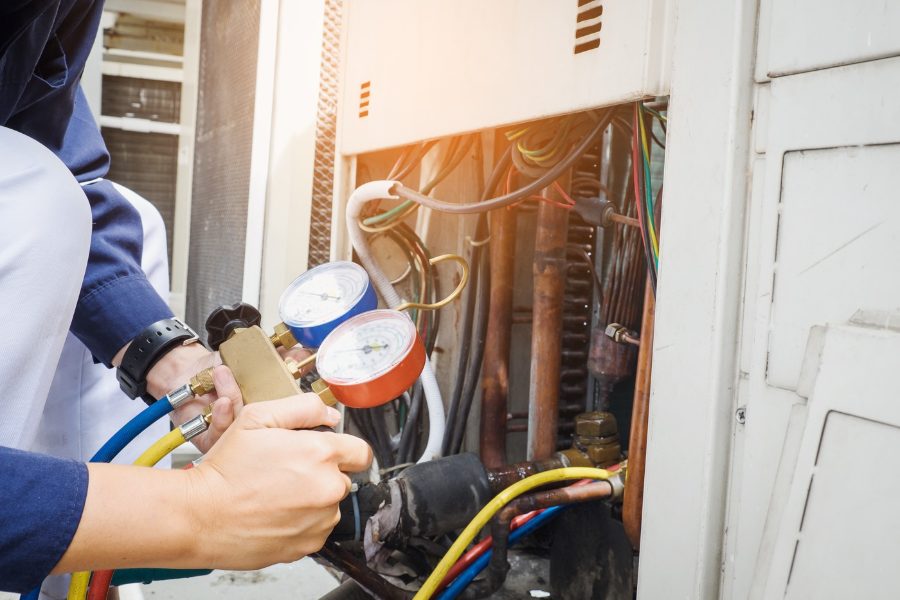 Hulgan technician checking refrigerant gauges during an AC repair in Perry, Iowa